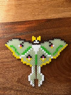 a close up of a butterfly made out of legos on a wooden surface,