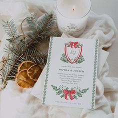 the wedding stationery is surrounded by pine cones, cinnamons, and candles on a white blanket