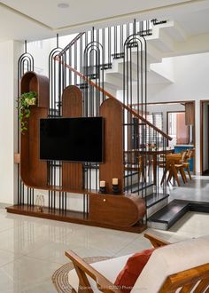 a living room filled with furniture and a flat screen tv mounted on a wall next to a stair case