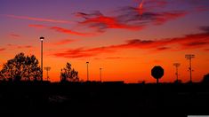 an orange and purple sky at sunset with street lights