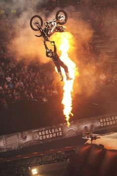 a man flying through the air while riding a bike on top of a fire pit