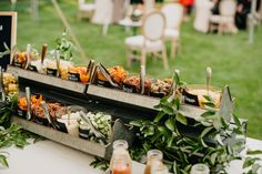 an assortment of food is on display at a wedding or event with greenery in the foreground