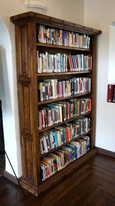 a bookshelf filled with lots of books sitting on top of a hard wood floor