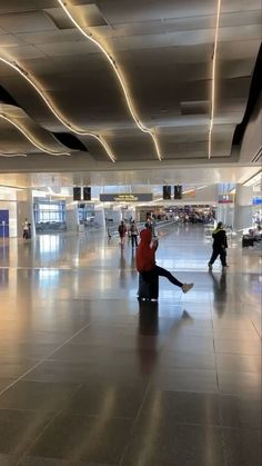 people are walking through an airport terminal with their feet on the luggage bag and one person is sitting down