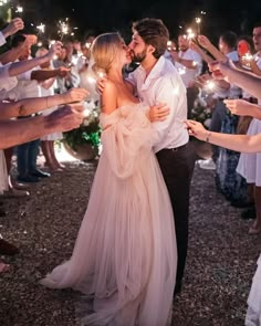 a man and woman kissing while holding sparklers in front of their faces as they are surrounded by other people