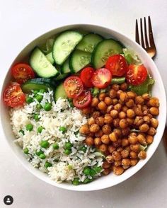 a white bowl filled with rice, cucumbers, peas, tomatoes and chickpeas