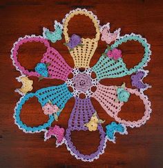 a crocheted doily on a wooden surface with flowers and leaves in the center