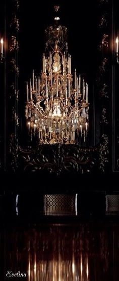 an ornate chandelier in a dark room with lights on the wall and floor