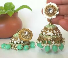 Big mint Green Jhumka Earrings with Hand painted vibrant colors Jhumka in antique gold plating are beautiful and looks elegant on any occasion will surely galvanize you, because our products are unique, comfortable, fashion forward & very popular for the rich look.  Base Metal of our product is copper  Length 6.5cm Width 3cm JEWELLERY CARE Protect your Jewellery from Sharp Blows, Scratches and Extreme Temperatures. Avoid Contact With Perfumes, Sprays, Chemicals and Water. Keep your Jewellery in a Clean, Dry and Airtight Box. Wipe it using a Soft Cloth Regularly.Discover a variety of Necklace sets and Earring  only at Azzashiny.fj . Our Jewelry  Sets are made from metal & alloys like Copper or Brass respectively. Azzashinyfj  has exclusive craftsmanship into designing & implementing necklac Green Temple Jewelry Style Jhumkas For Eid, Green Temple Jewelry Jhumkas For Eid, Green Bollywood Jhumkas With Intricate Design, Traditional Green Jhumkas For Eid, Festive Green Jhumkas With Intricate Design, Heavy Green Jhumkas For Eid, Green Meenakari Jhumkas For Navratri, Green Jhumkas With Intricate Design For Gift, Bohemian Gold Meenakari Jhumkas