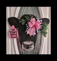 a door hanger with a cow wearing a pink bow on it's head