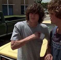 two men standing next to each other near a car