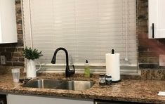 a kitchen with white cabinets and granite counter tops, along with a black faucet