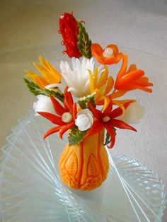 there is a vase with flowers in it sitting on a glass plate, ready to be used as a centerpiece