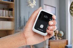 a hand holding a smart phone in front of a book shelf with books on it