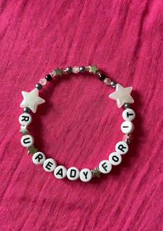 a beaded bracelet with white stars and the words ready to be spelled on it