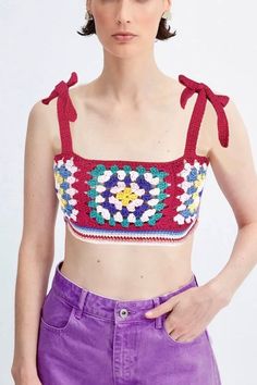 a woman wearing purple pants and a crop top with crocheted flowers on it