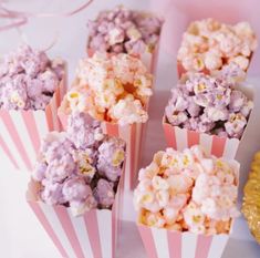 pink and white striped paper popcorn boxes filled with purple and yellow popcorn kernels on a table