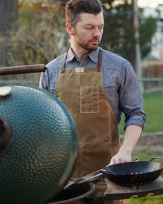 a man in an apron grilling on top of a bbq with a large green egg