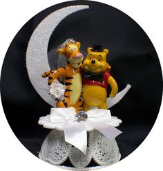 a couple of winnie the pooh figurines sitting on top of a moon