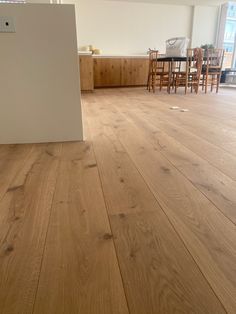 an empty room with wooden floors and white walls in the center is a dining table and chairs