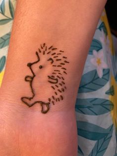 a small tattoo on the foot of a person with a hedgehog face drawn on it