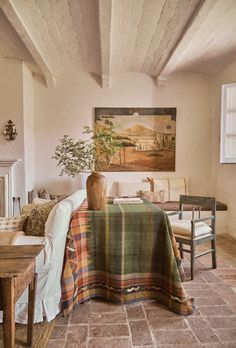 a living room filled with furniture and a table covered in a plaid blanket next to a fire place