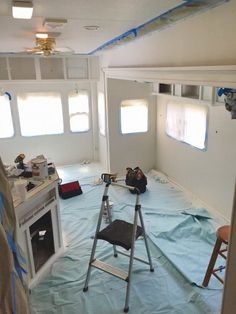 the inside of a house being remodeled with blue tarp on the floor and windows