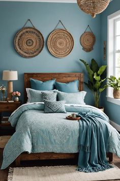 a bed with blue sheets and pillows in a bedroom next to two plants on the wall