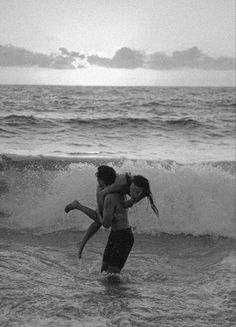 two people are playing in the water at the beach