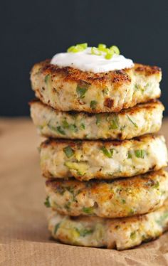 four crab cakes stacked on top of each other with sour cream and green onions in the middle