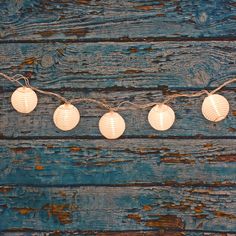 some paper lanterns are hanging on a string against a blue wooden background with twine