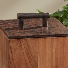 a wooden box sitting on top of a table next to a potted green plant