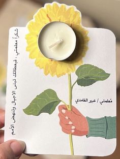 a person holding a small card with a candle and a sunflower on the front