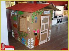 a cardboard house with flowers on the roof and doors painted to look like a dollhouse