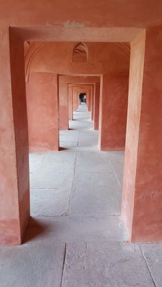 an empty hallway with pink walls and cement floors