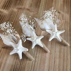 three white starfishs are sitting on a wooden table next to shells and seaweed