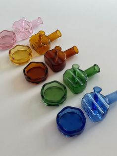 six different colored glass vases sitting next to each other