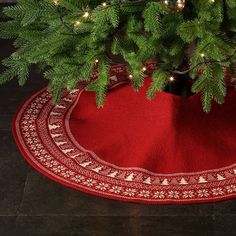 a christmas tree skirt on the floor with lights around it and a potted plant