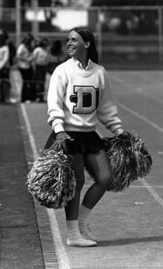 a woman standing on top of a tennis court holding cheerleader pom poms