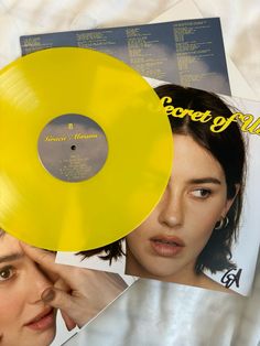 a yellow vinyl record sitting on top of a magazine cover next to a photo of a woman