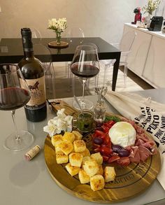 there is a wine glass and some food on the table with two bottles of wine