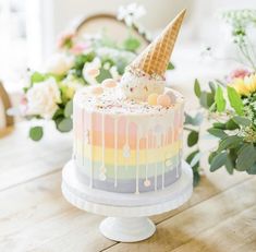 an ice cream cake with sprinkles and rainbow icing on a wooden table