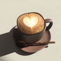 a cup of coffee on a saucer with a heart shaped foam in the middle