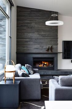 a living room with two couches and a television mounted on the wall next to a fire place