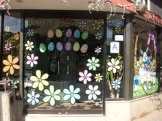 a store front with flowers painted on the glass and decorated in different colors, shapes and sizes