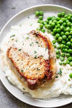 a white plate topped with meat, mashed potatoes and peas