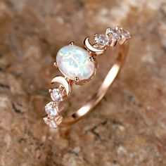 an opal and diamond ring sitting on top of a rock