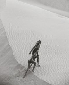 a woman is standing in the sand with skis on her feet and head down