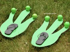 two pairs of flip flops with green balls on them sitting in the grass next to each other