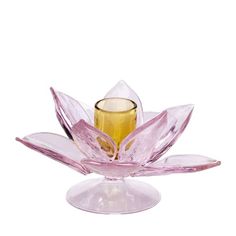 a glass candle holder sitting on top of a pink flower shaped object with a gold center